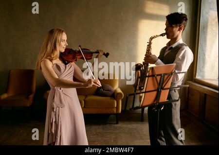 Young female violinist and male saxophonist training at home Stock Photo