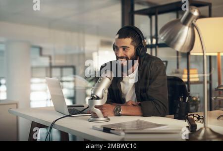 Lets keep the dialogue going. a young man using a headset, microphone and laptop during a late night at work. Stock Photo