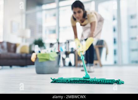 Cleanliness comes first in her home. a young woman mopping the floor at home. Stock Photo