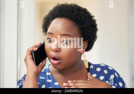 It takes one call for a rumour to start. a young businesswoman looking shocked while using a smartphone in a modern office. Stock Photo