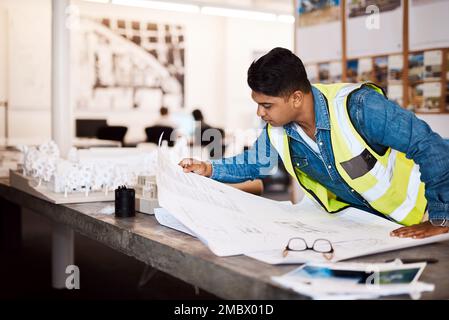 No one plans better than him. a young architect looking at a blueprint in his office. Stock Photo