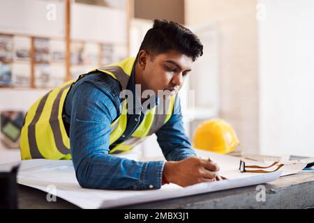 His designs never disappoint. a young architect drawing up a building plan in his office. Stock Photo