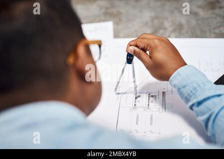 Its no wonder his designs are on point. an architect using a compass to draw a building plan. Stock Photo