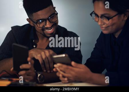Smarter technology for faster repairs. two young technicians using their smartphone while repairing computer hardware. Stock Photo