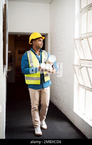 I have great plans for this building. a young engineer holding blueprints on a construction site. Stock Photo