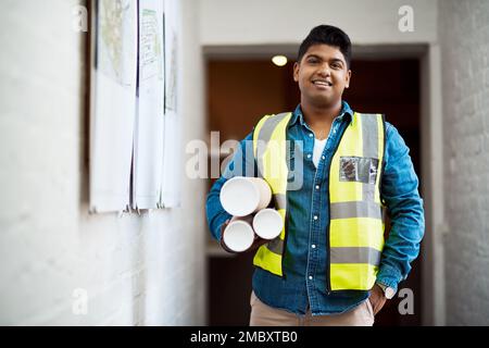 Im ready to put plan into action. a young engineer holding blueprints on a construction site. Stock Photo