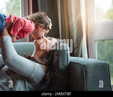 Relax, happy and kiss with mother and baby on sofa for bonding, quality time and child development. Growth, support and trust with mom and daughter in Stock Photo