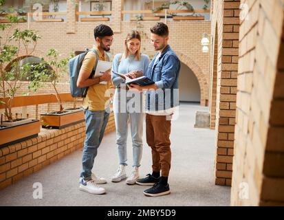 University, students and friends with textbook for project study, education or sharing information together at the campus. Group of college people Stock Photo