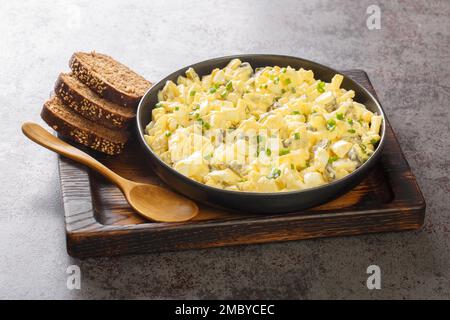 Eiersalat is a creamy German egg salad with cubes of crisp apple and crunchy sour pickles. closeup on the wooden board on the table. Horizontal Stock Photo