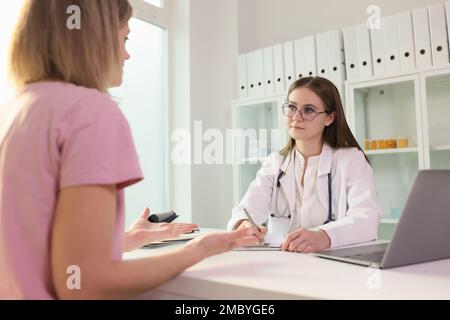 Doctor communicating with female patient in clinic and listening to her complaints Stock Photo
