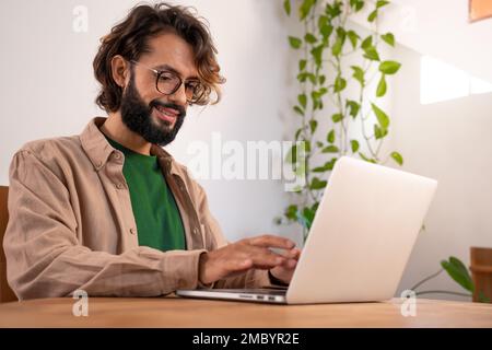 Cheerful male writer working on a novel on his laptop at home thinking stories for a book. Stock Photo