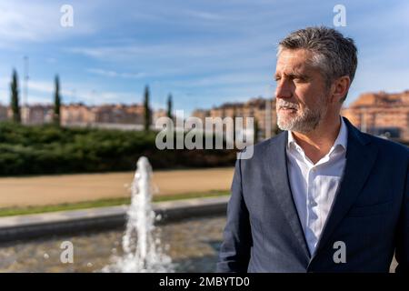 Thoughtful senior businessman with gray hair wearing formal suit standing near fountain and looking away while admiring amazing scenery Stock Photo