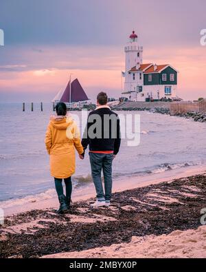 Paard van Marken Lighthouse in the Netherlands, couple visiting the fishing village of Marken Holland during sunset in the winter Stock Photo