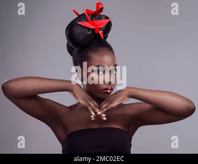 Beauty is power - the right makeup enhances that. Studio portrait of a beautiful young woman wearing Asian inspired makeup and posing with origami Stock Photo