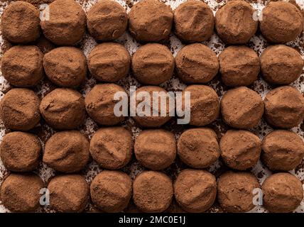 Chocolate truffle candy background. Rows of tasty truffle balls texture. Gourmet candies of dark chocolate in cocoa powder. Sweet food dessert. Stock Photo