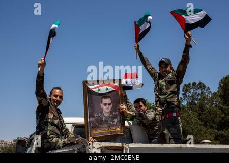 FILE - Syrian soldiers hold up Baath party flags and a portrait of Syrian President Bashar Assad with Arabic that reads 'Yes to the leader of victory,' as they celebrate outside the town of Douma, in the eastern Ghouta region, near the Syrian capital Damascus, Syria, Wednesday, May 26, 2021. With its war on Ukraine now in its third week, Russian President Vladimir Putin on Friday, March 11, 2022, approved bringing in volunteer fighters from the Middle East into the conflict. (AP Photo/Hassan Ammar, File)
