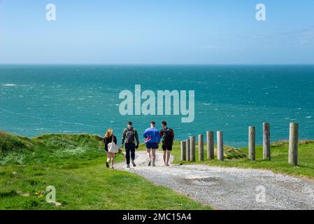 Four young people walking on the coast path near Morfa Nefyn on the Lleyn Peninsula, North Wales. Stock Photo