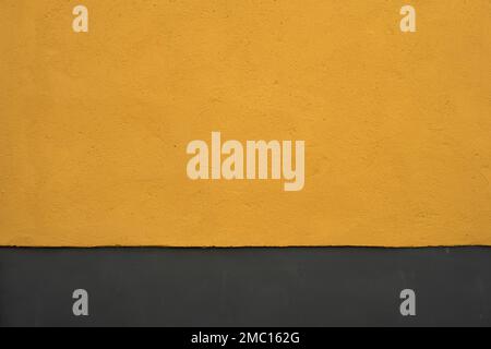 Yellow painted concrete wall with gray colored skirting board Stock Photo