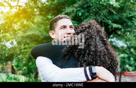 Close up of happy couple hugging in nature, Close up of smiling teenage couple hugging, Teenage couple hugging outdoors Stock Photo