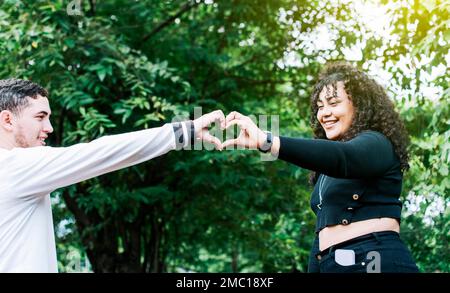 Young couple making heart shape with hands, Happy couple making heart shape with hands, Two friends outdoors making heart shape with hands Stock Photo