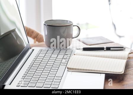notepad and ballpoint pen on laptop computer, work from home concept Stock Photo
