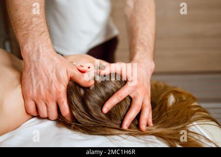 A man is a chiropractor doing a massage to a woman in the neck and trapezius  muscles in his office Stock Photo - Alamy