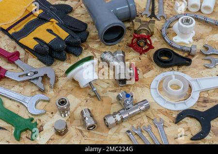 Plumbing tools, parts, pipeline components and gloves on the background of a construction OSB plate. Stock Photo