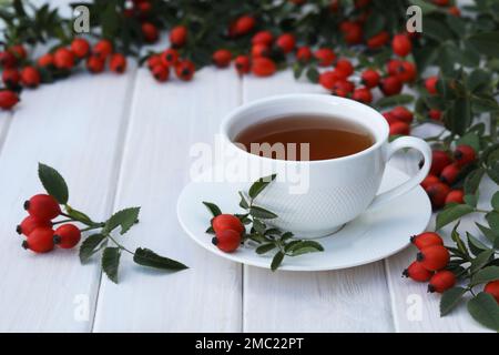 Cup of tea with rose berries on a white wooden background Stock Photo