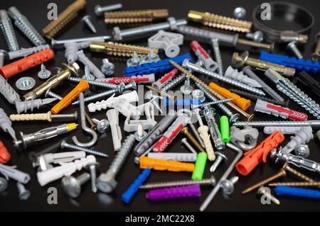 Different types of fasteners on a dark wood background. Front view. Stock Photo