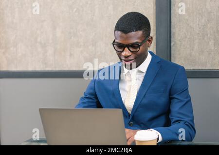 Smiling professional black business man using laptop computer working in office. Stock Photo