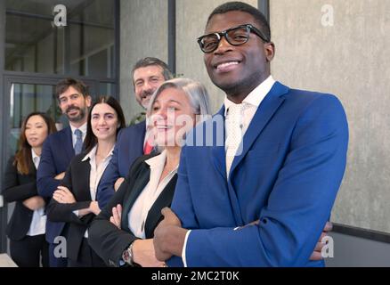 Diverse team of happy young people standing together. Multi-ethnic group of colleagues standing in line, arms folded and smiling. Concepts of teamwork Stock Photo