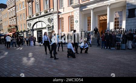 London - 02 27 2022: Girls finish dancing with shuffle dance ending movement in covent garden with people around Stock Photo