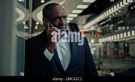 African American middle-aged adult man boss company CEO entrepreneur businessman talking phone answer call serious talk financial advisor broker Stock Photo