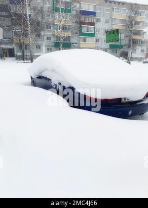 Car covered with snow, close-up. A passenger car in winter was covered with snow after a snow storm. Car in the parking lot near the house Stock Photo