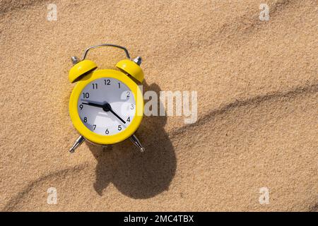 Alarm clock on the sand in the desert on a sunny day with a shadow Stock Photo