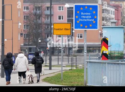 18 January 2023, Brandenburg, Frankfurt (Oder): Passers-by walking from the city bridge pass the yellow city entrance sign and the blue sign 'Federal Republic of Germany'. In the background, residential and commercial buildings can be seen on Slubice Street (federal road B5). Photo: Soeren Stache/dpa Stock Photo
