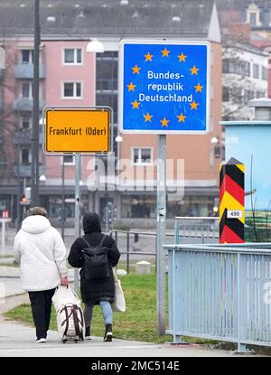 18 January 2023, Brandenburg, Frankfurt (Oder): Passers-by walking from the city bridge pass the yellow city entrance sign and the blue sign 'Federal Republic of Germany'. In the background, residential and commercial buildings can be seen on Slubice Street (federal road B5). Photo: Soeren Stache/dpa Stock Photo