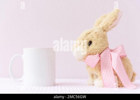 Easter mockup white mug with rabbit on pink cover background Stock Photo