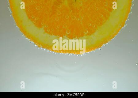 Close-up of juicy orange slice on white background. Slice of orange slice in sparkling water on white background, close-up. Horizontal macro image. Stock Photo