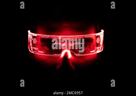 The young man is using virtual reality glasses. Portrait of man wearing backlit glasses while playing game. Stock Photo