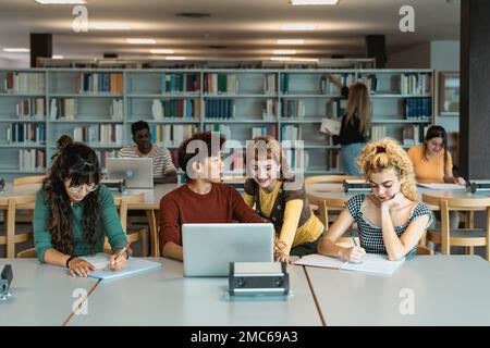 Young university students using laptop and studying with books in library - School education concept Stock Photo