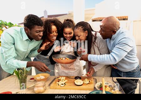 Happy African family preparing food recipe together on house patio Stock Photo