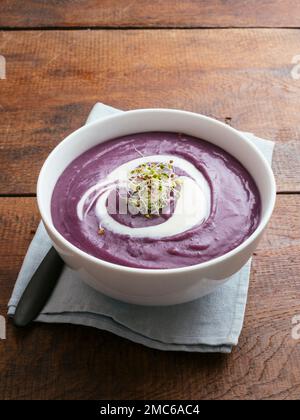 Purple potato soup with soy yogurt and sprouts. Stock Photo