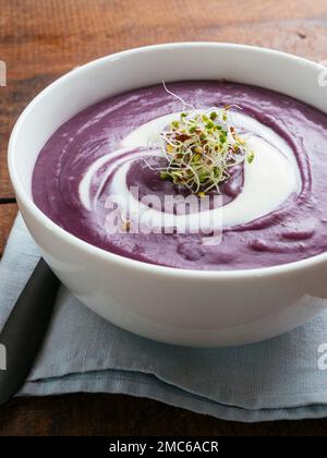 Purple potato soup with soy yogurt and sprouts. Stock Photo