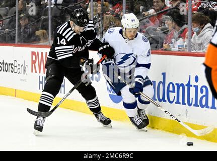 Tampa Bay Lightning defenseman Mikhail Sergachev (98) controls the puck as  he is checked by New Jersey Devils right wing Nathan Bastian (14) during  the first period of an NHL hockey game