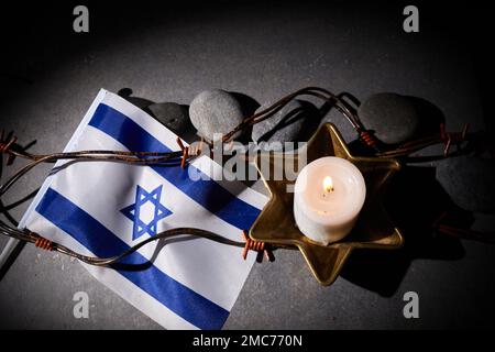 Burning candle, Barbed wire, flag of Israel on dark background. Holocaust memory day Stock Photo