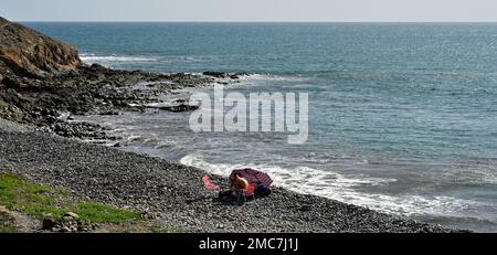Umbrella windbreak on pebble beach of  Playa de Triana which is noted for sunset photos, Las Palmas, Gran Canaria Stock Photo