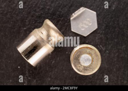 Three metal weights for old jewelry scales on slate stone, macro, top view. Stock Photo