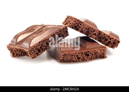 Pieces of broken aerated chocolate on a white background close-up. Chocolate Stock Photo