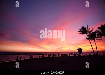 Tourists watching a dramatic sunset at Poipu Beach on the tropical island of Kauai Stock Photo